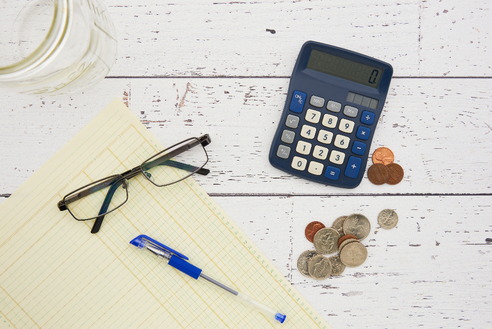 Calculator, coins, and notepad for estimating a mortgage payoff