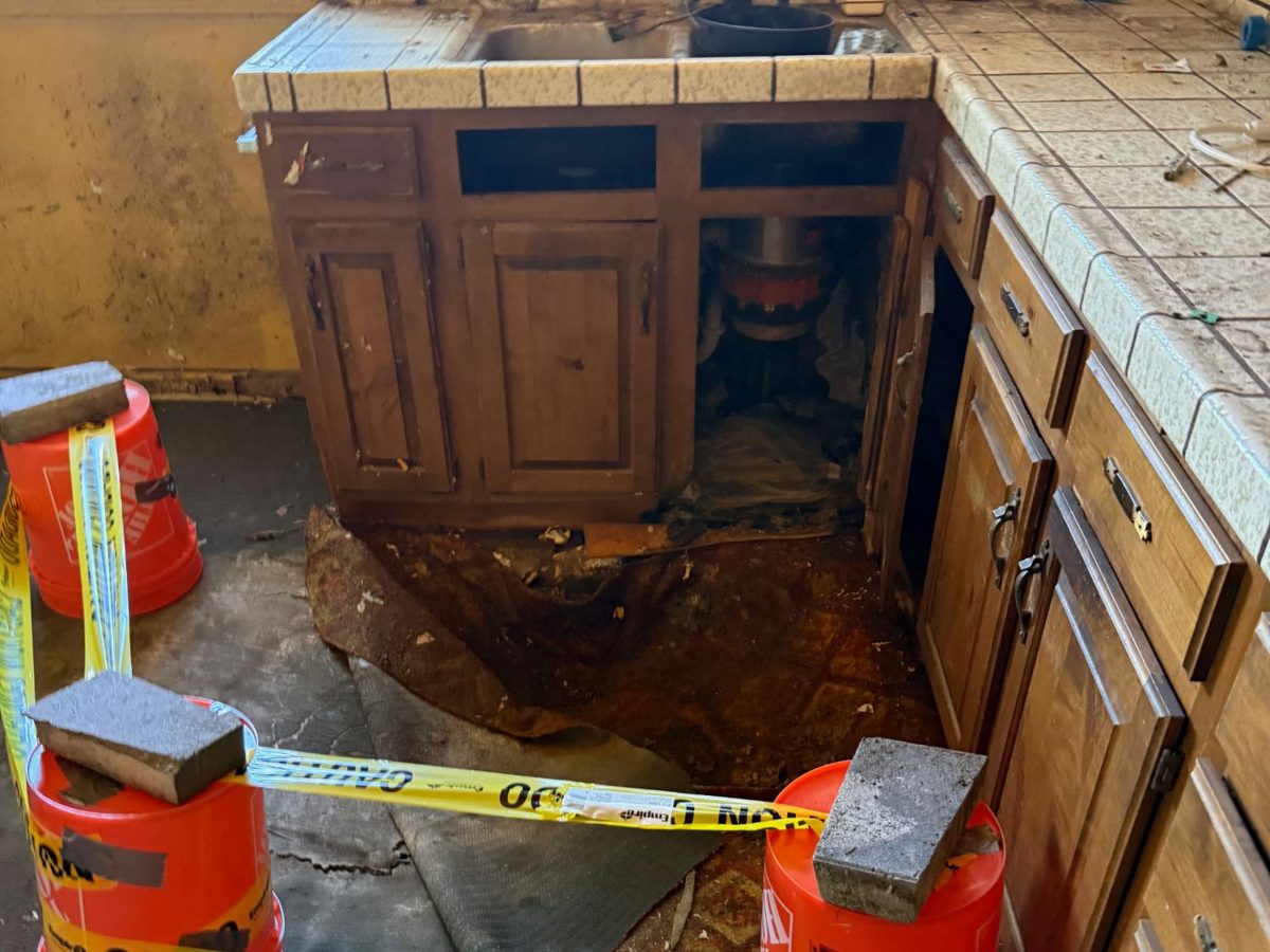 Kitchen with water-damaged flooring and worn cabinets in an inherited California house we bought